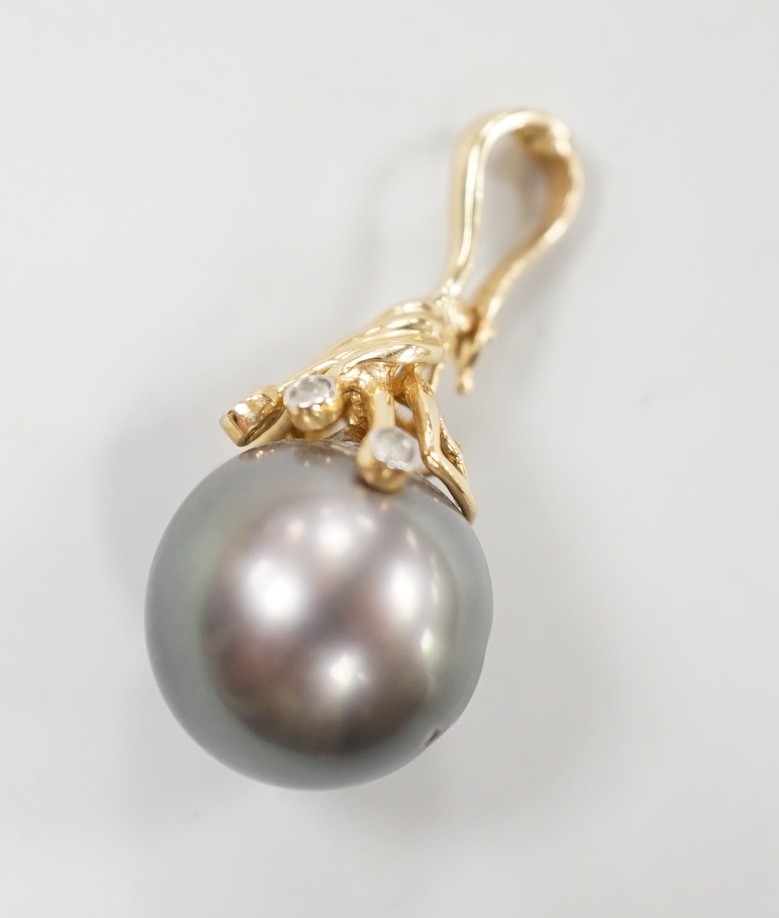 A modern 585 yellow metal, single stone Tahitian pearl and five stone diamond chip set pendant, pearl diameter 13.6mm, 30mm, gross weight 5.4 grams.